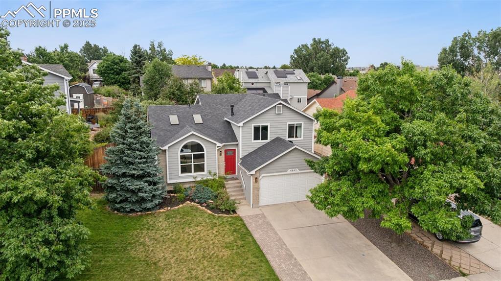 Caption: View of front facade with a shingled roof, driveway, a garage, and a residential view