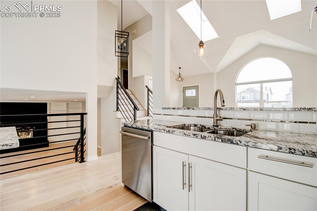 Image 12 of 32: Kitchen featuring a skylight, stainless steel dishwasher, light stone count