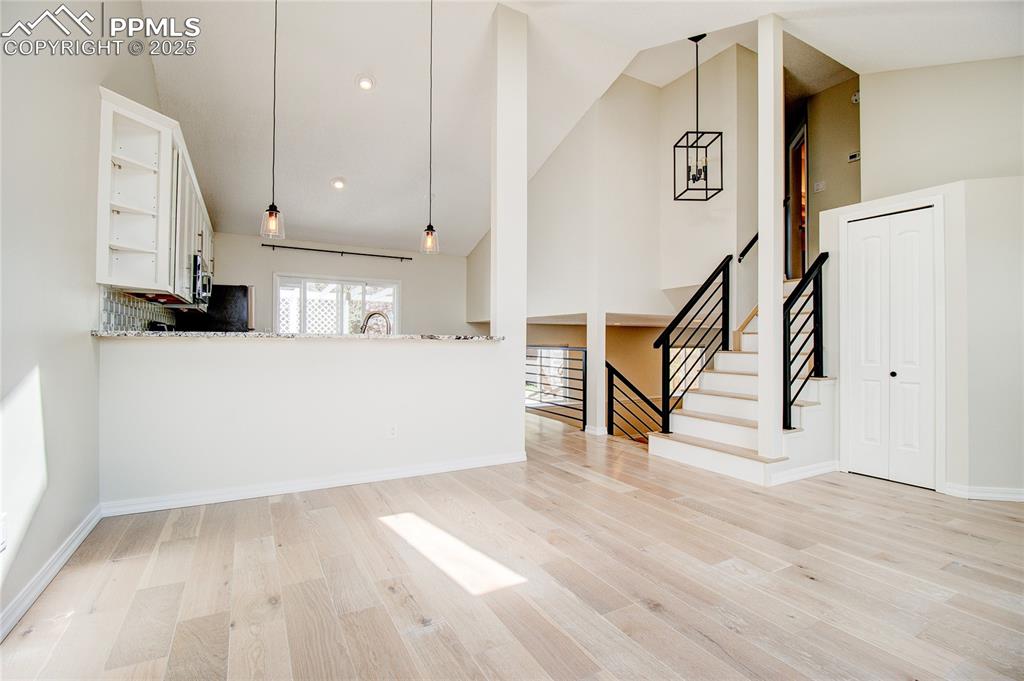Image 13 of 32: Unfurnished living room with high vaulted ceiling, light wood-style floors,