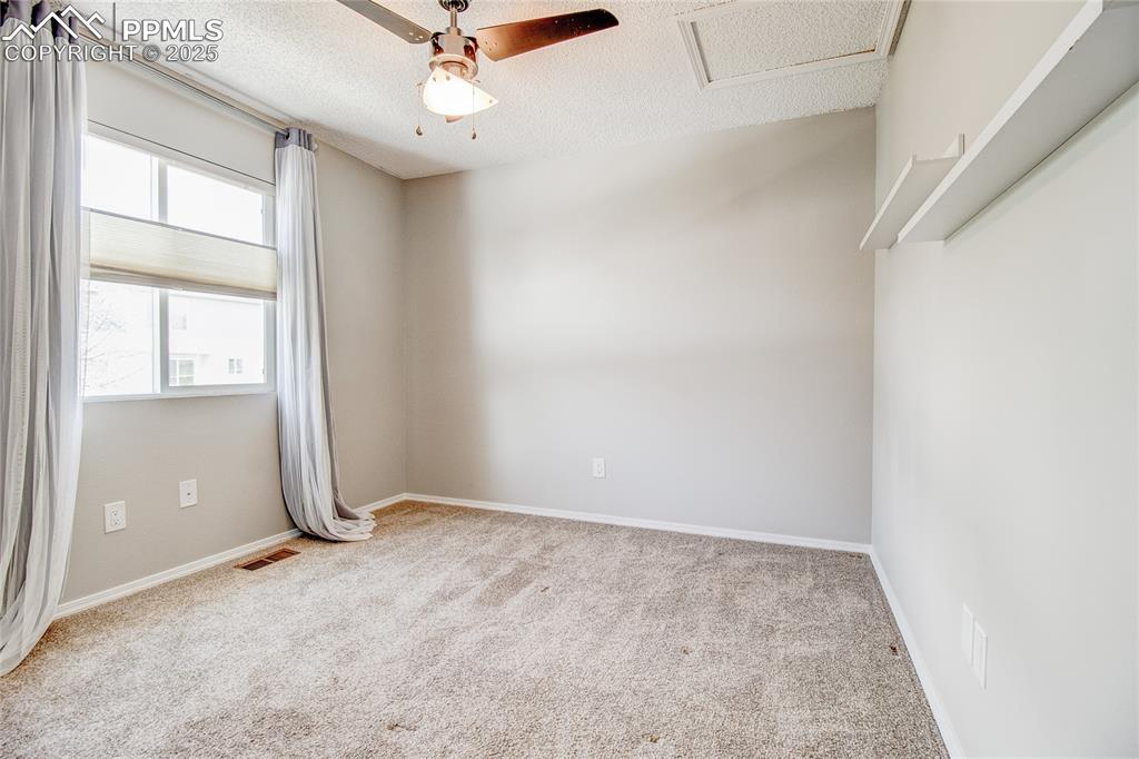 Image 16 of 32: Empty room with carpet flooring, a textured ceiling, ceiling fan, and attic