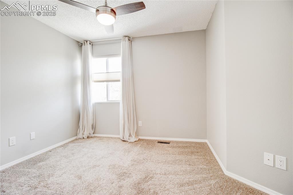 Image 17 of 32: Empty room featuring carpet floors, a textured ceiling, and a ceiling fan