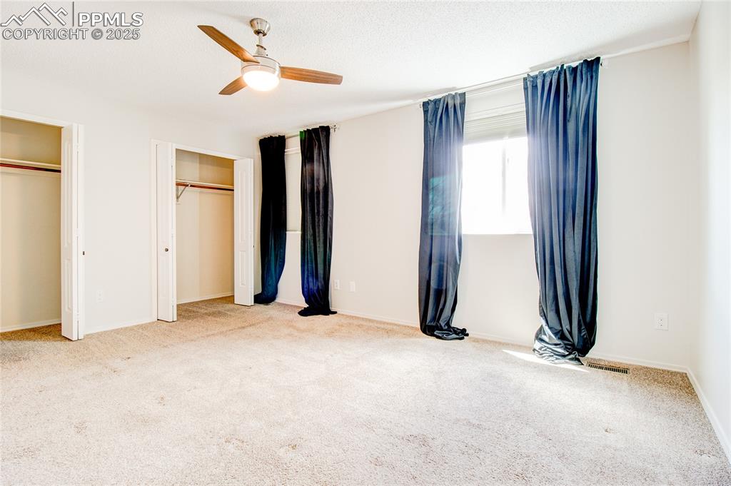 Image 18 of 32: Unfurnished bedroom featuring two closets, carpet floors, and a ceiling fan
