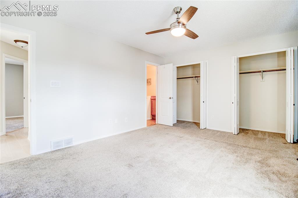 Image 19 of 32: Unfurnished bedroom featuring two closets, carpet flooring, and ceiling fan