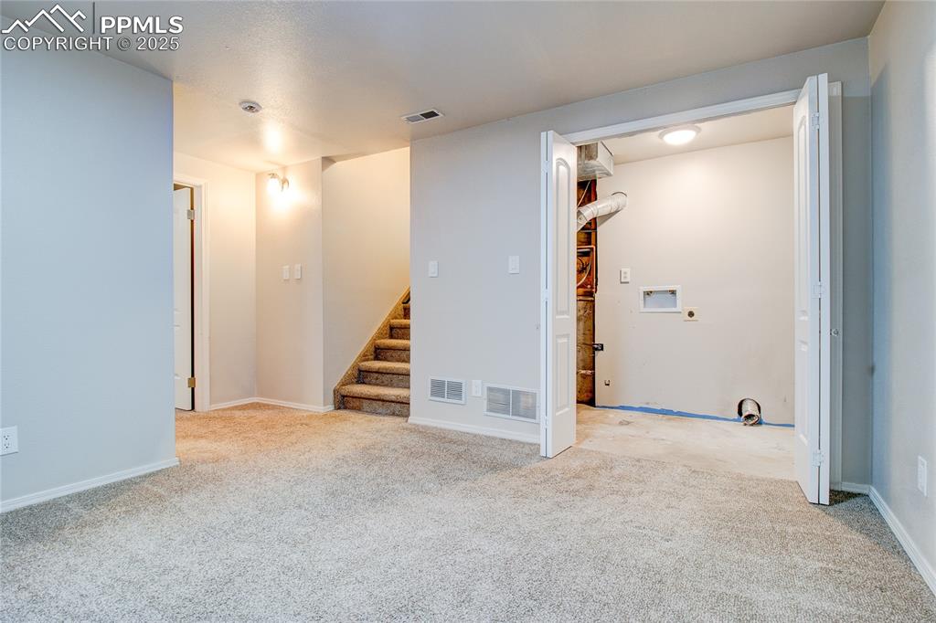 Image 25 of 32: Unfurnished room with light carpet and stairs