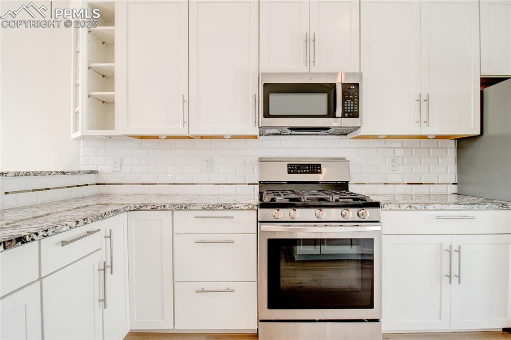 Image 3 of 32: Kitchen with appliances with stainless steel finishes, open shelves, white