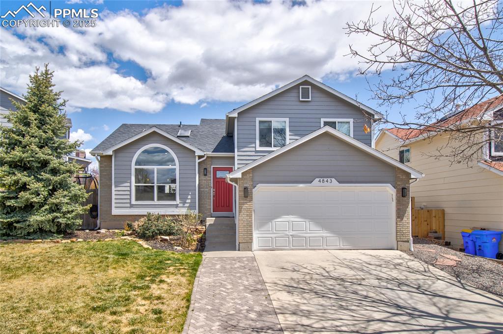 Image 6 of 32: Split level home featuring concrete driveway, brick siding, a garage, and a