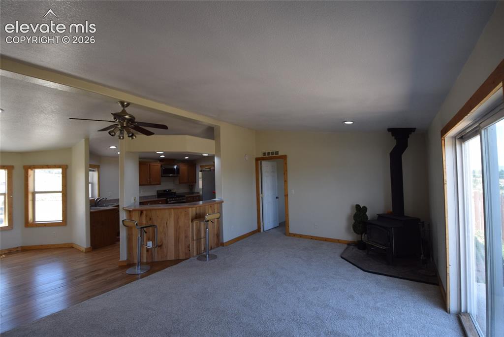 Image 12 of 48: Open-concept living space featuring wood-finish flooring, a wood-burning st