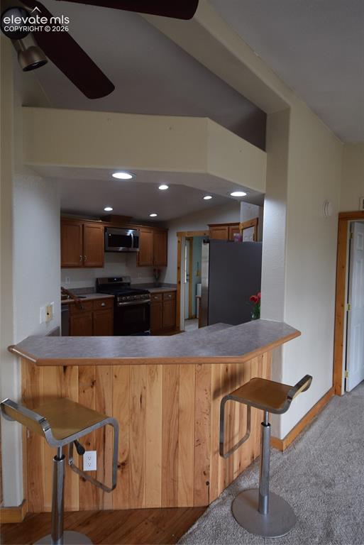 Image 13 of 48: Kitchen pass-through with wood-paneled breakfast bar, recessed lighting, an