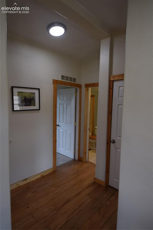 Image 19 of 48: Wood-finish flooring with natural wood trim and white paneled doors