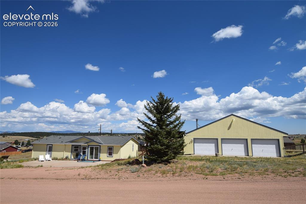 Image 2 of 48: Single-story residence featuring a detached three-car garage and a paved pa
