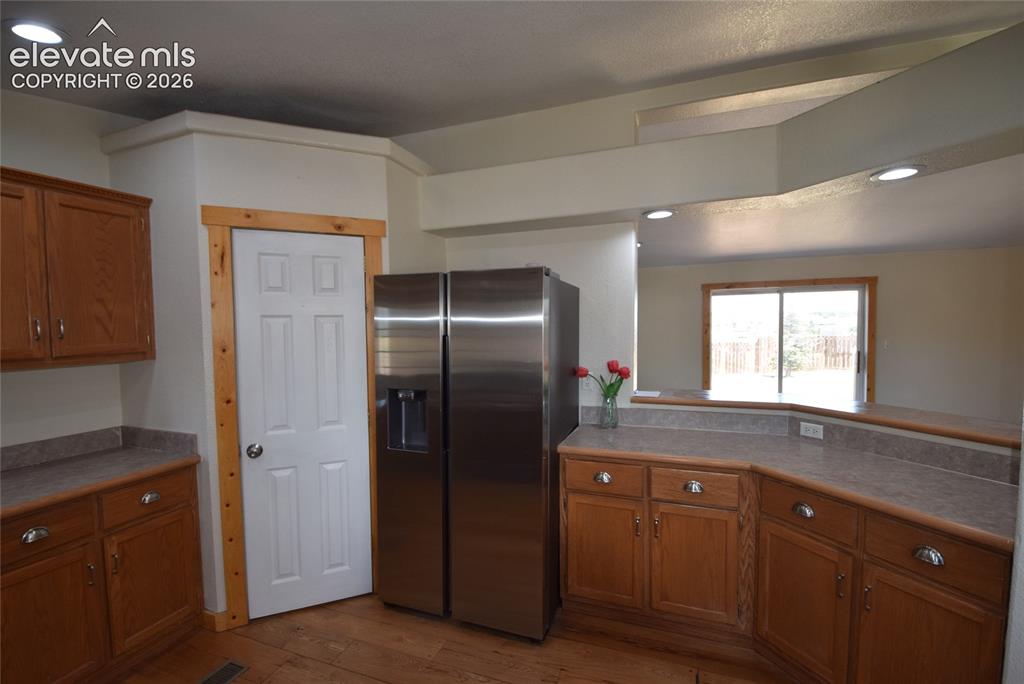Image 22 of 48: Kitchen featuring wood-finish flooring, wood cabinetry with silver-tone har