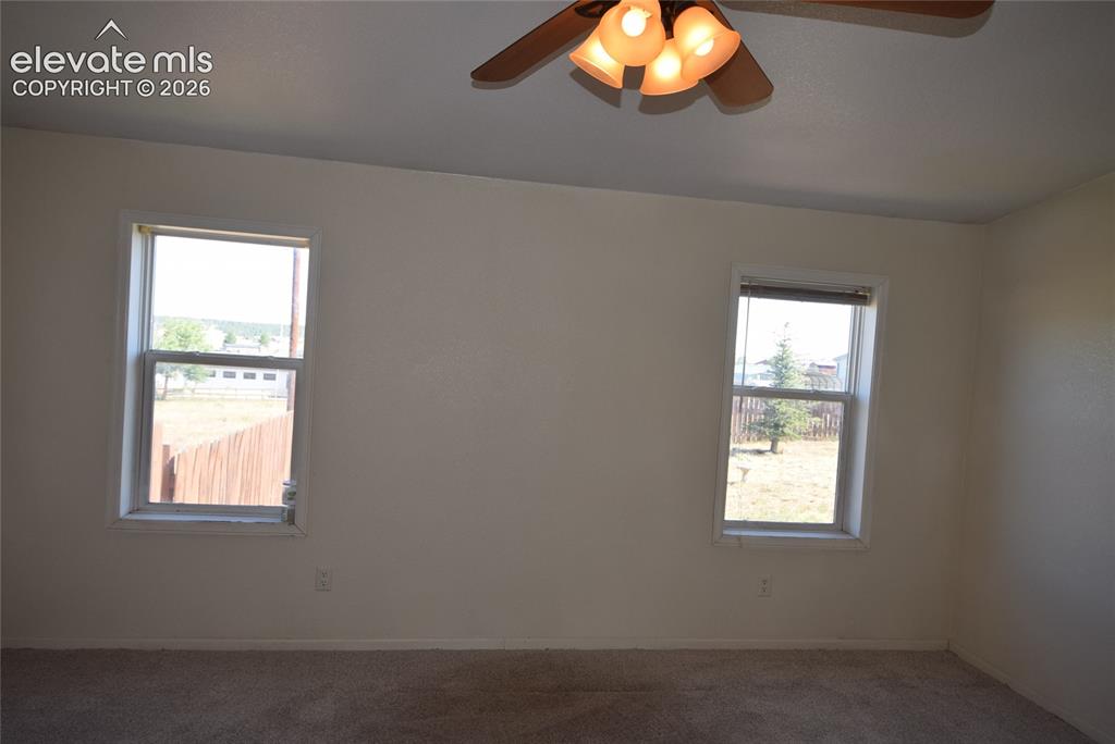 Image 27 of 48: Carpeted flooring with white wall finishes, two windows, and a ceiling fan 