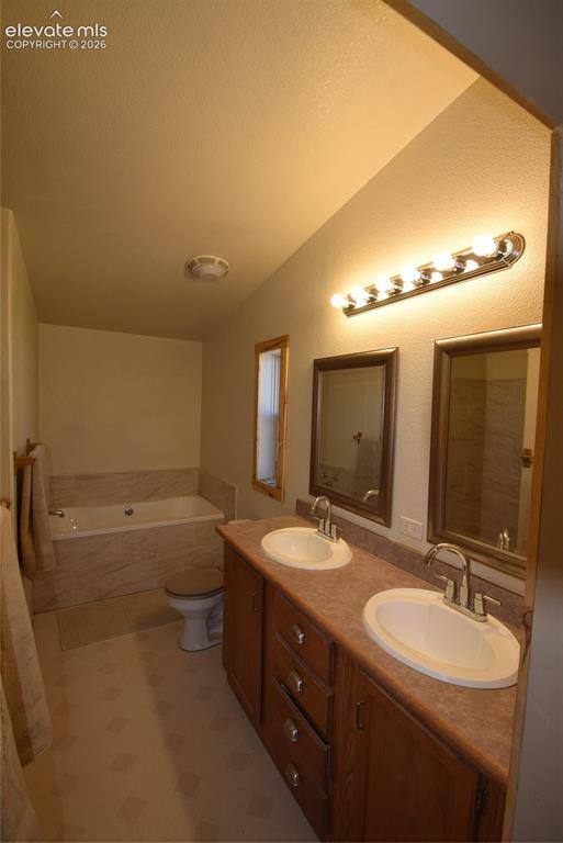 Image 32 of 48: Double vanity with integrated sinks, wood-finish cabinetry, countertop, and