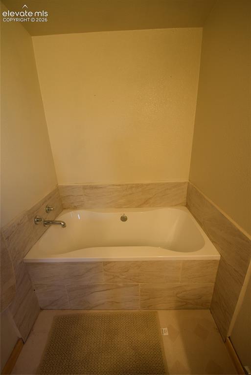 Image 33 of 48: Built-in soaking tub with chrome fixtures, surrounded by light-toned tile