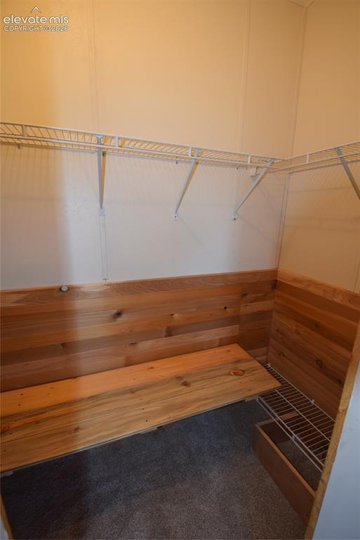 Image 35 of 48: Wood-paneled storage nook with integrated bench seating, wire shelving, and