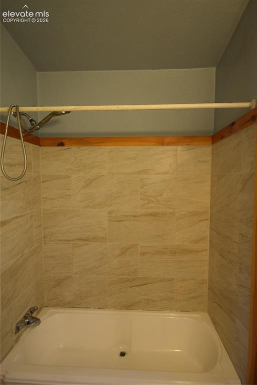 Image 39 of 48: Tub/shower combination featuring a chrome shower head with a flexible hose 