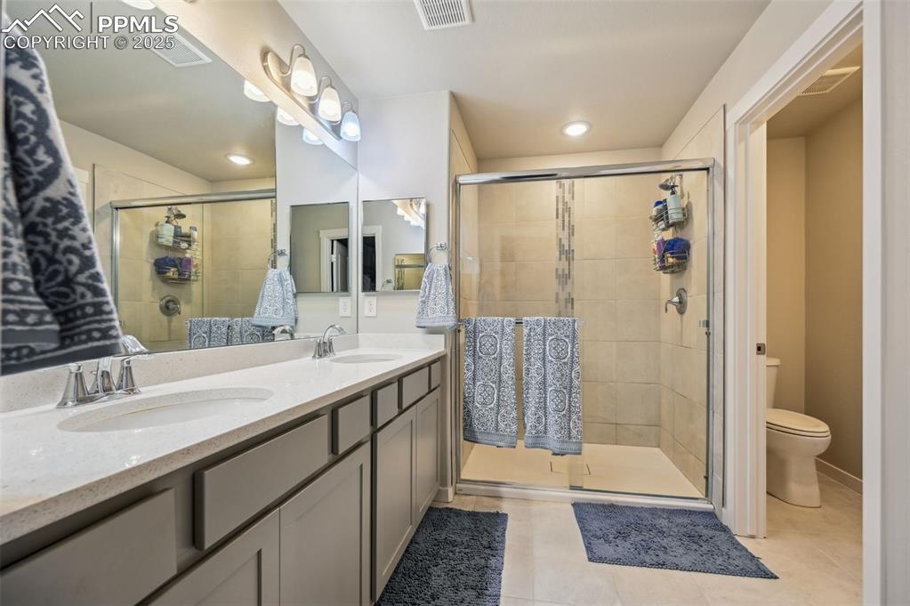Image 10 of 46: Bathroom featuring double vanity, light tile patterned flooring, a stall sh