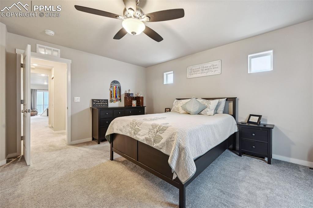 Image 12 of 46: Bedroom with multiple windows, light colored carpet, and ceiling fan