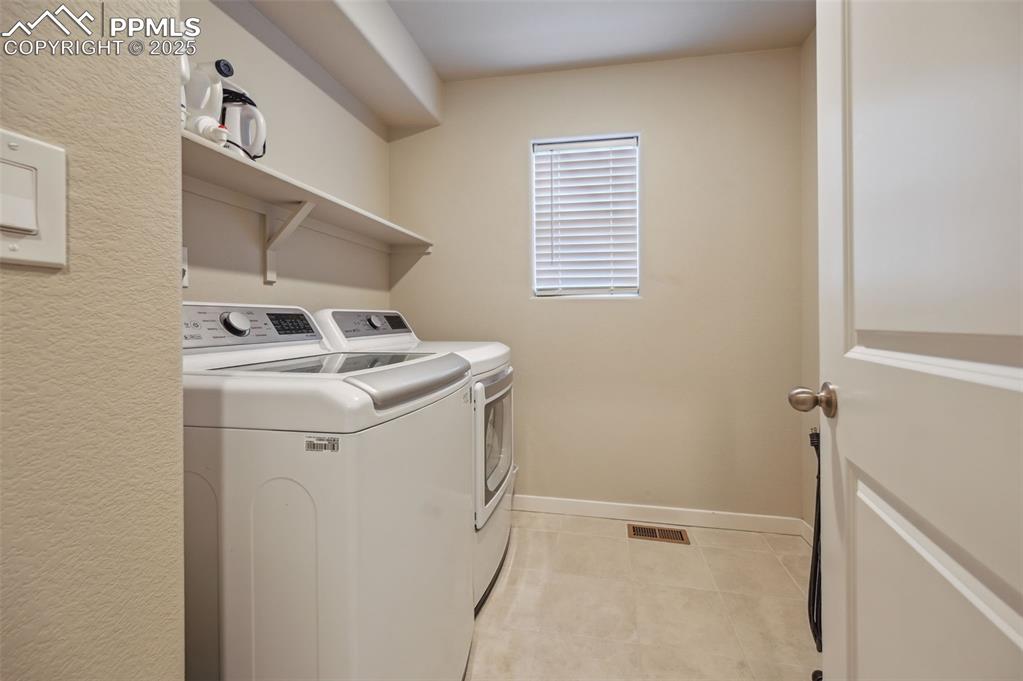 Image 13 of 46: Washroom featuring light tile patterned flooring and washing machine and cl