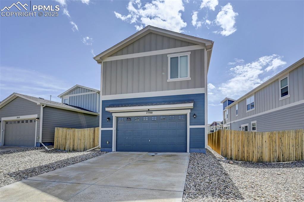 Image 2 of 46: View of front of home with board and batten siding, driveway, and a garage