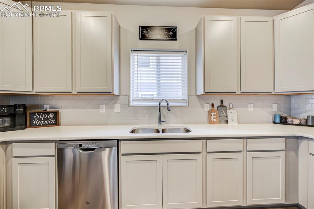 Image 22 of 46: Kitchen featuring dishwasher, decorative backsplash, light stone countertop