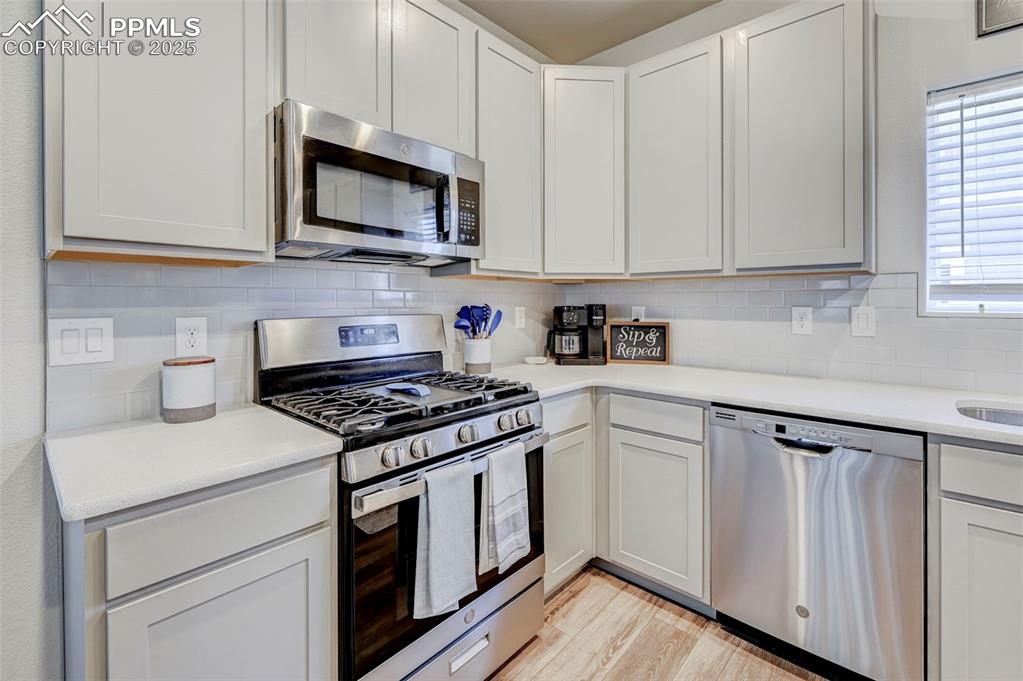 Image 23 of 46: Kitchen featuring stainless steel appliances, backsplash, light stone count