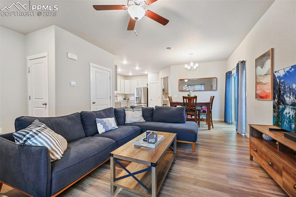 Image 25 of 46: Living room featuring wood finished floors, a chandelier, and a ceiling fan