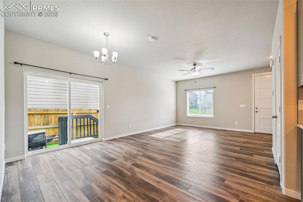 Image 30 of 46: Unfurnished room with dark wood-type flooring, ceiling fan, and a chandelie