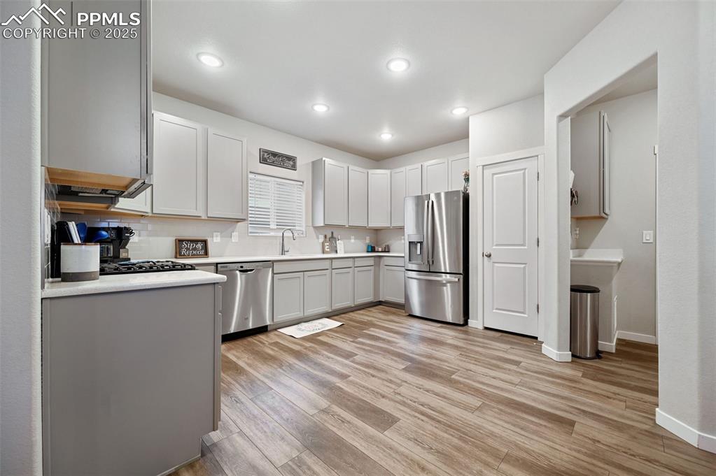 Image 4 of 46: Kitchen featuring gray cabinets, backsplash, stainless steel appliances, li