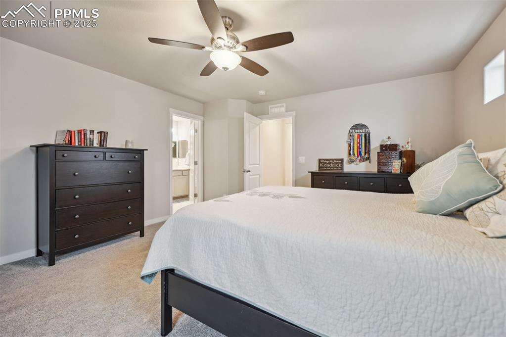Image 9 of 46: Bedroom featuring light colored carpet, ceiling fan, and connected bathroom