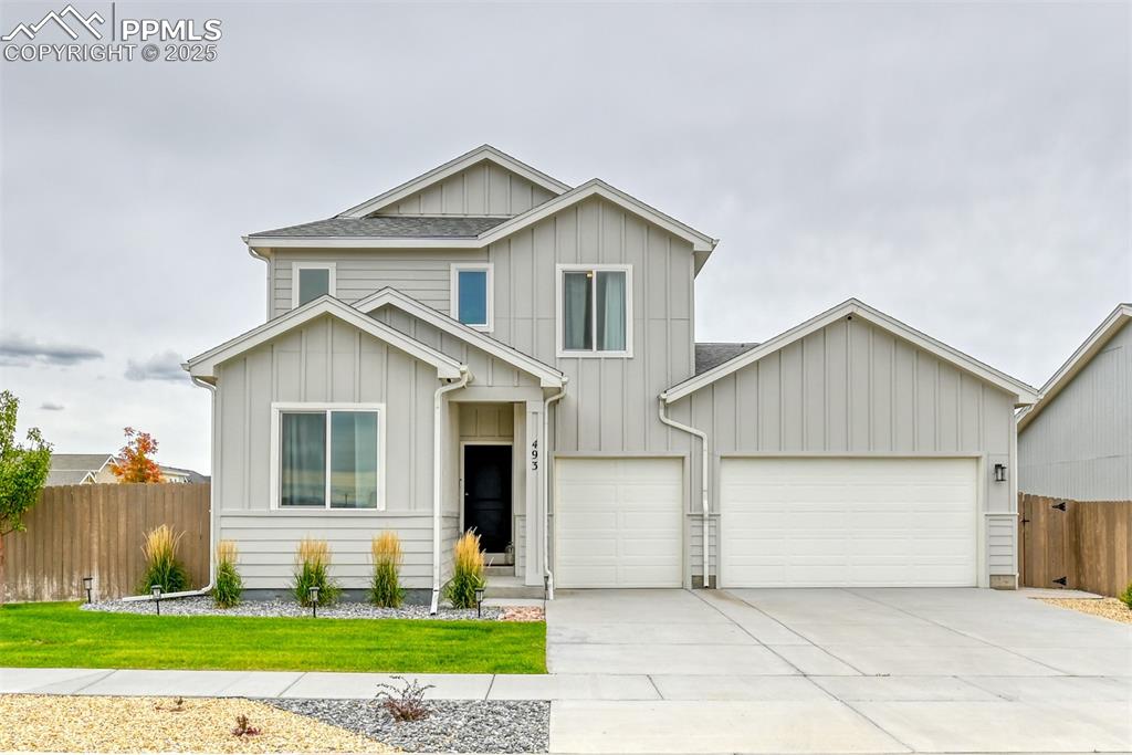 Image 22 of 50: View of front of property featuring board and batten siding, driveway, roof
