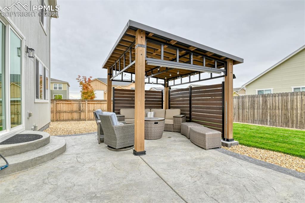 Image 29 of 50: Fenced backyard with an outdoor hangout area and a patio