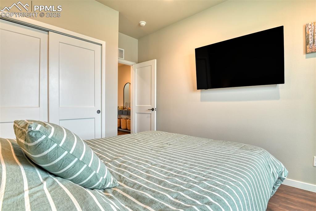 Image 34 of 50: Bedroom with dark wood-style floors and a closet