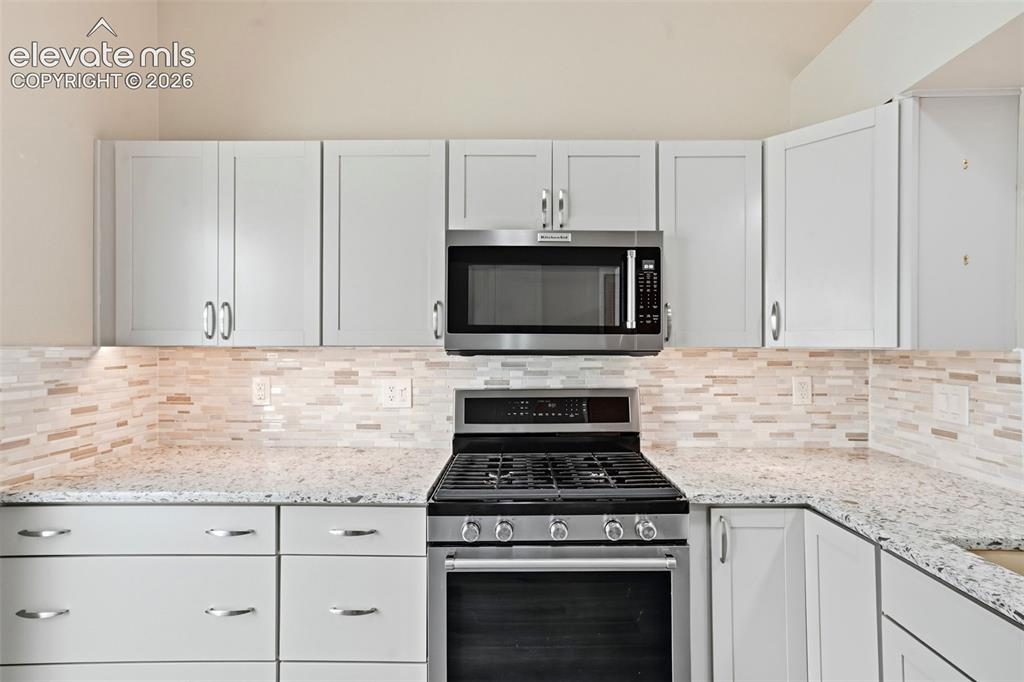 Image 13 of 49: Tasteful tile backsplash and plenty of cabinet space