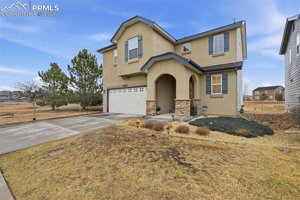 Image 1 of 18: Front of home featuring stucco and stone and beautiful landscaping