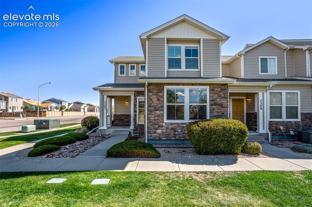 Caption: Multi-level exterior with stone and siding accents, featuring a covered front entry, established lan