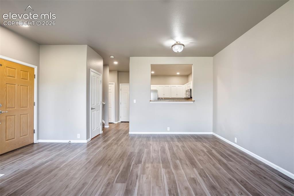 Image 10 of 50: Spacious room with wood-finish flooring, recessed lighting, and a pass-thro