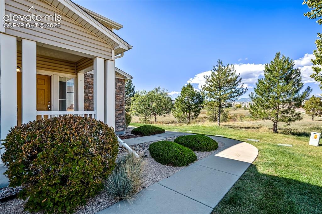 Image 3 of 50: Covered entryway featuring columns, stone accents, and wood-finish door