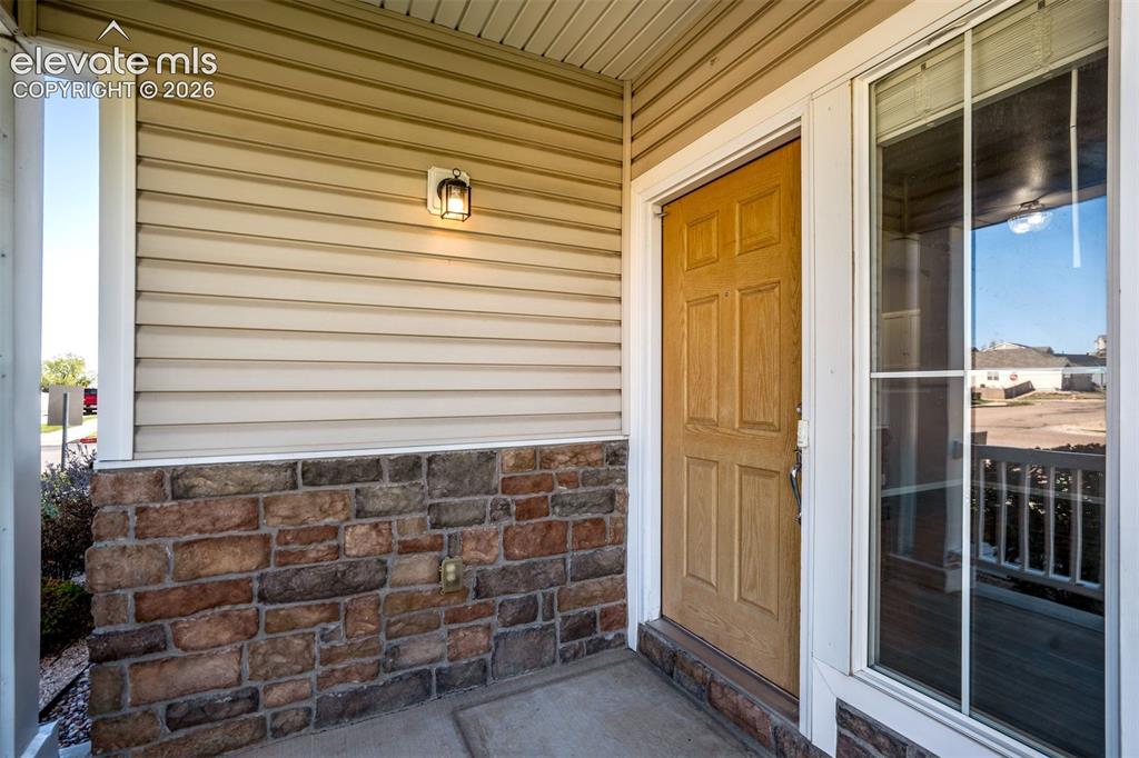 Image 5 of 50: Tan horizontal siding complemented by stone veneer detailing
