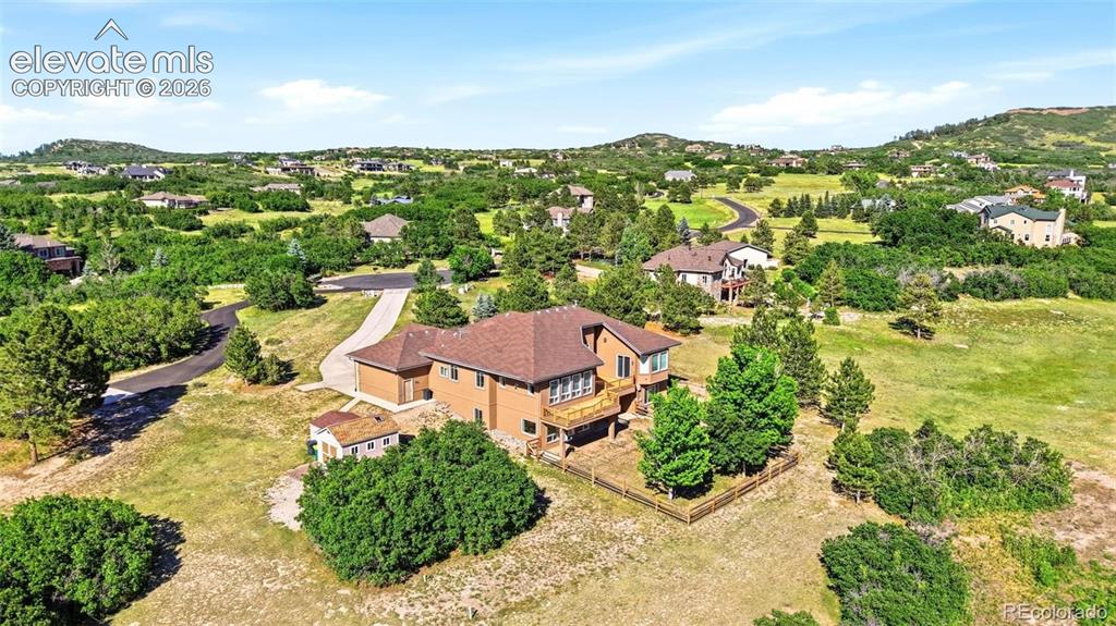Caption: Expansive property featuring a multi-level residence with a large deck, attached garage, and a long 