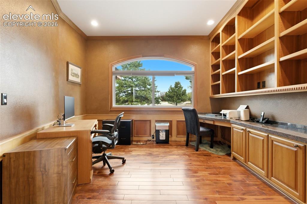 Image 10 of 46: Wood-finish flooring with built-in cabinetry, an arched window, and custom 
