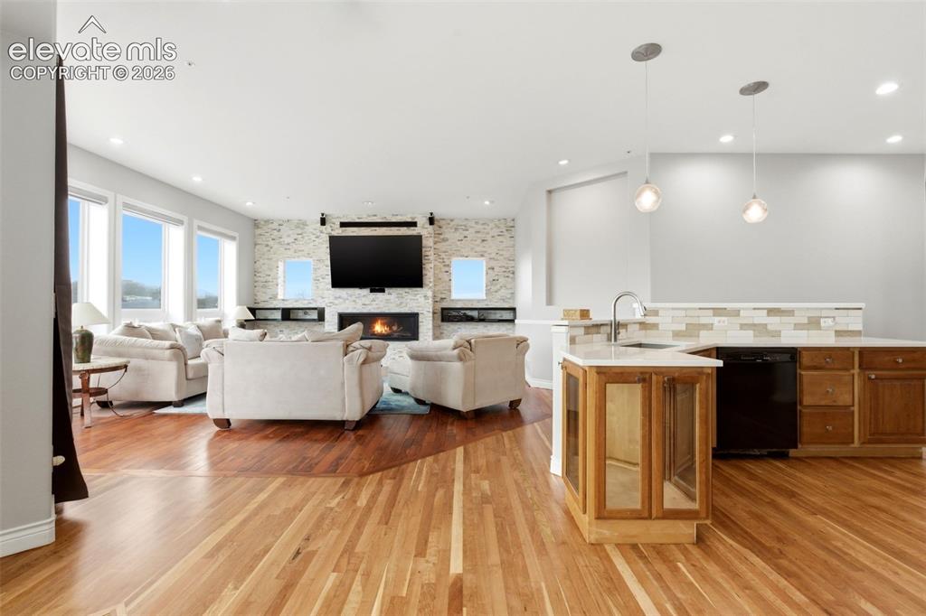 Image 15 of 46: Hardwood flooring throughout, a stacked stone fireplace, recessed lighting,