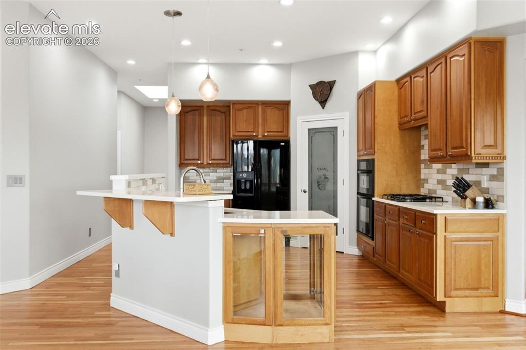Image 19 of 46: Kitchen featuring wood cabinetry, light-toned countertops, a tile backsplas