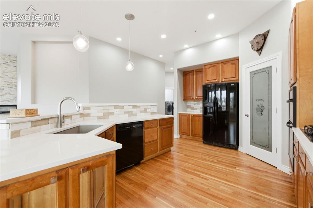 Image 2 of 46: Kitchen featuring wood-finish flooring, white countertops, a mosaic tile ba