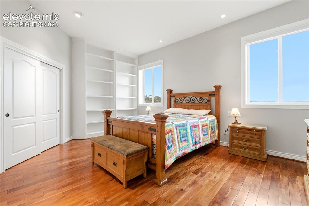 Image 28 of 46: Wood-finish flooring, recessed lighting, built-in shelving, and white frame