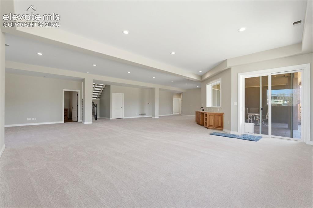 Image 33 of 46: Expansive carpeted area with recessed lighting, built-in wooden cabinetry, 
