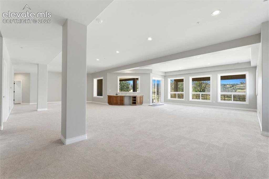 Image 34 of 46: Expansive open-concept room featuring light-toned carpeting, recessed light
