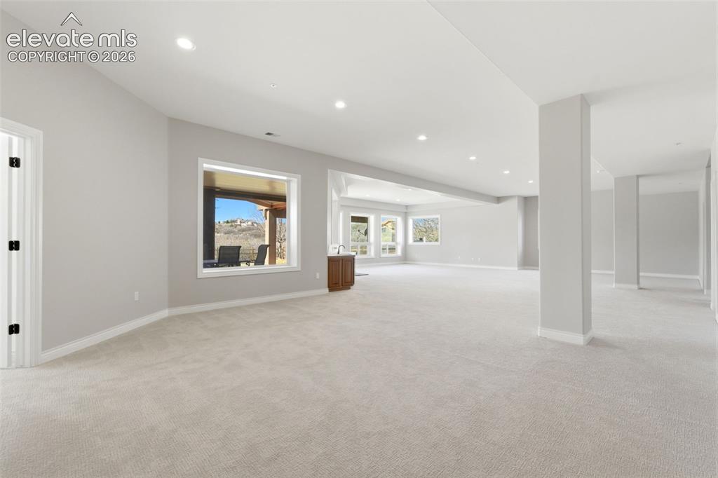 Image 36 of 46: Expansive open room with neutral carpeting, recessed ceiling lighting, and