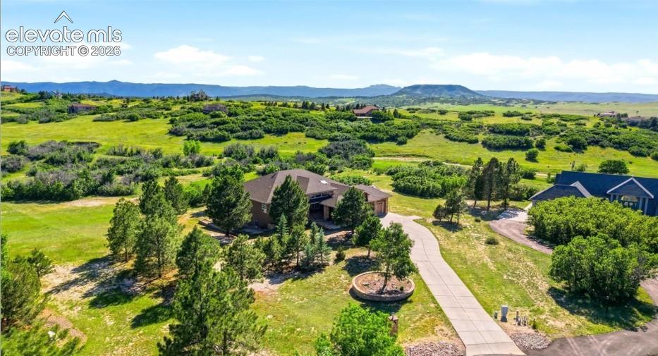 Image 44 of 46: Spacious property with a winding driveway, mature trees, and a mountain bac
