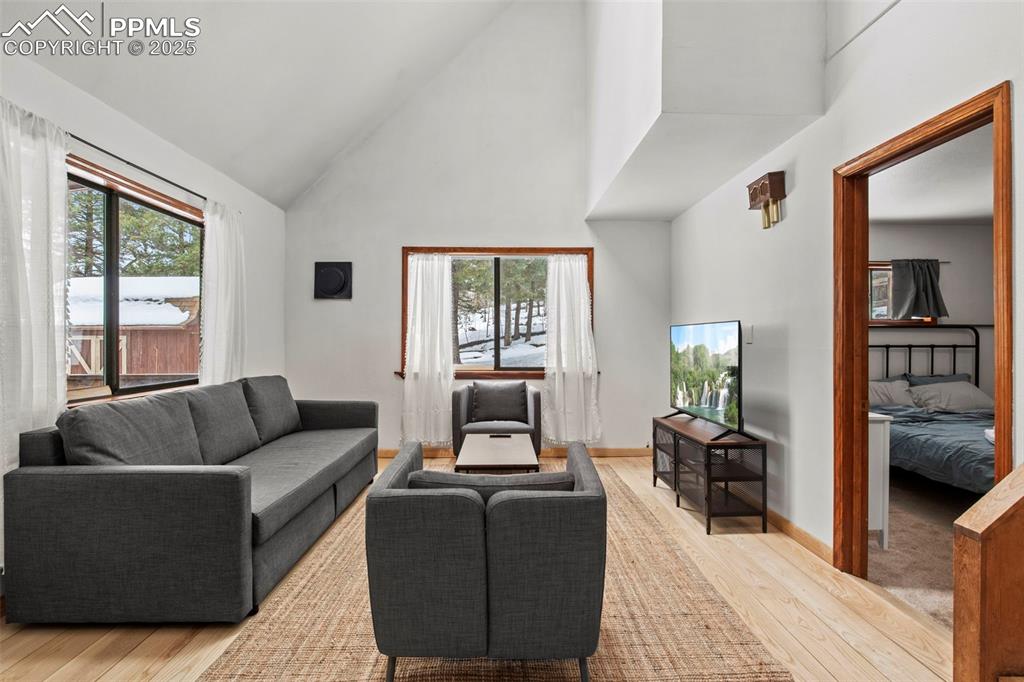 Image 10 of 50: Living area featuring high vaulted ceiling and hardwood / wood-style floors
